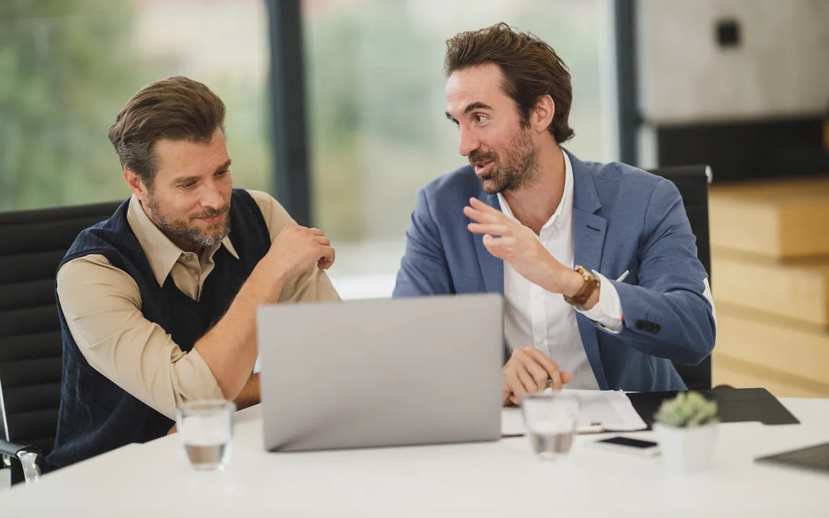 Twee ondernemers bekijken samen een voorstel op een laptop